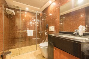 A modern bathroom with a glass-enclosed shower, a toilet, and a sink with a black countertop. - Caesar Hotel Oman (Muscat)