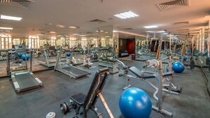 A gym with various exercise equipment, mirrors, and a skylight. - Caesar Hotel Oman (Muscat)