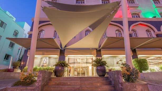 A hotel entrance with a grand staircase, large potted plants, and a canopy structure. - Caesar Hotel Oman (Muscat)