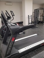 Un gimnasio con una bicicleta estática, una cinta de correr y una máquina de pesas.