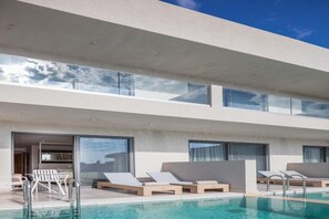 Ein modernes Hotel mit Poolbereich auf dem Dach, inklusive Liegestühlen und einem gläsernen Balkon.