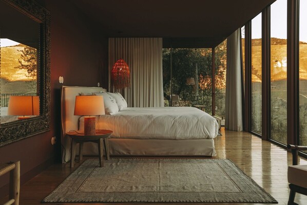 A bedroom with a large bed, a bedside table with a lamp, a mirror, and a view of the outdoors. - Ventozelo Hotel (São João da Pesqueira)