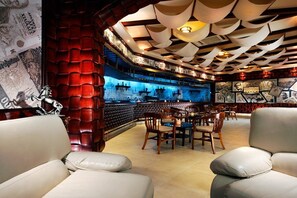 Un espace bar avec un mur en briques rouges, des chaises en bois et un comptoir de bar illuminé de lumière bleue.