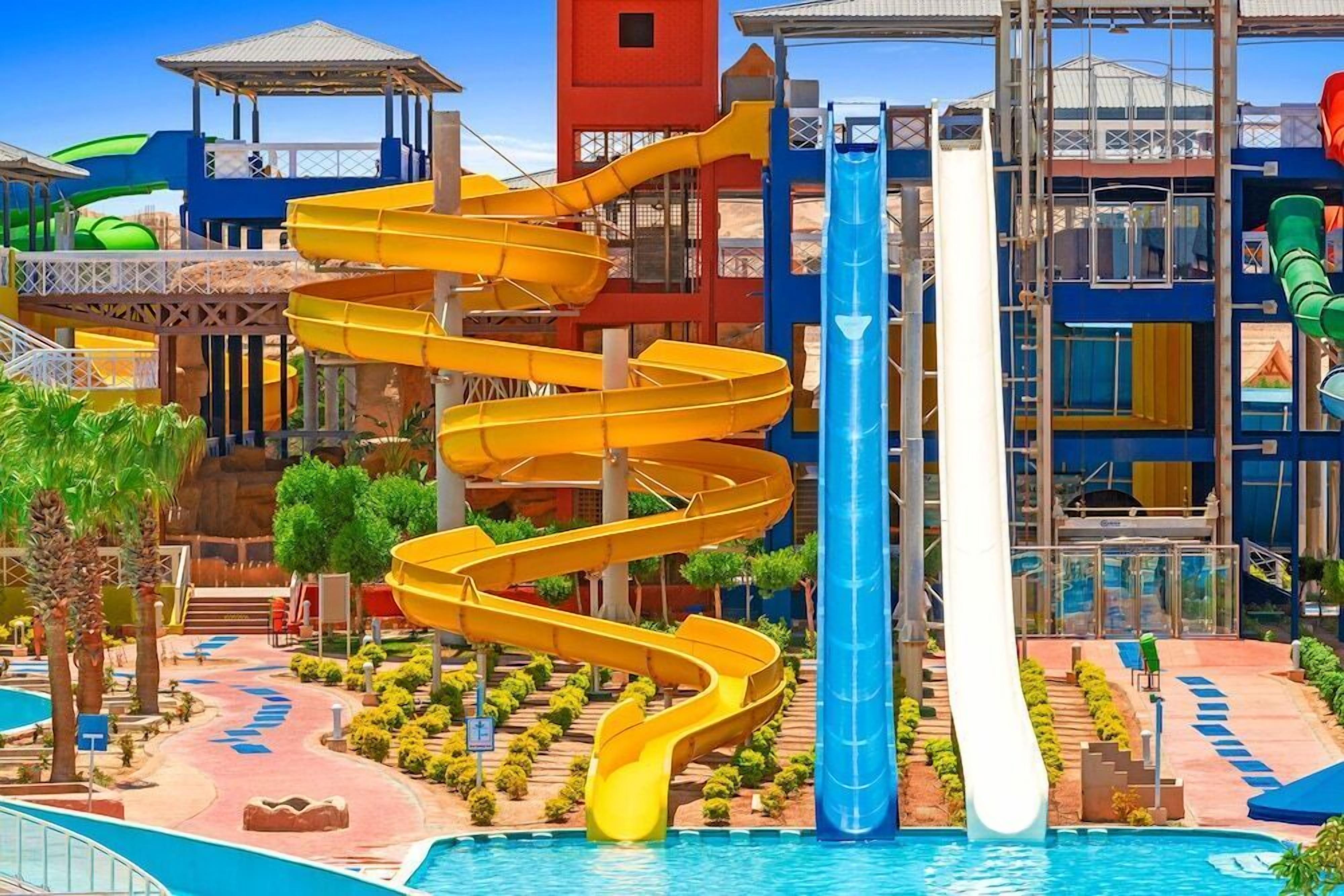 A water park with multiple slides, a pool, and a building with a red tower.