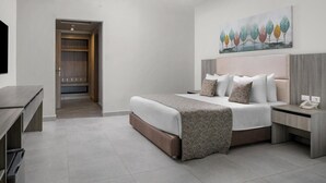 A modern hotel room with a large bed, a desk, a wardrobe, and a painting on the wall.
