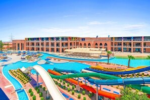 Un hôtel doté de nombreux balcons, d’un espace piscine avec toboggans et d’une plage.