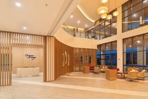 A hotel lobby with a reception desk, seating area, and large windows. - The Zenith Hotel Cameron (Tanah Rata)