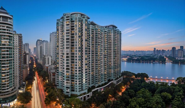 A high-rise building with multiple floors, surrounded by a river and other buildings. - Echarm Hotel (Guangzhou)