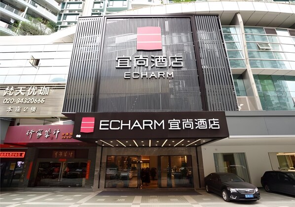 Ein Hotel mit moderner Fassade, das ein gut sichtbares Schild mit dem Namen 'ECHARM' und ein Logo zeigt.