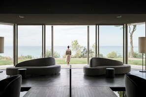 Un interior moderno con ventanas amplias, un sofá y vista al mar.