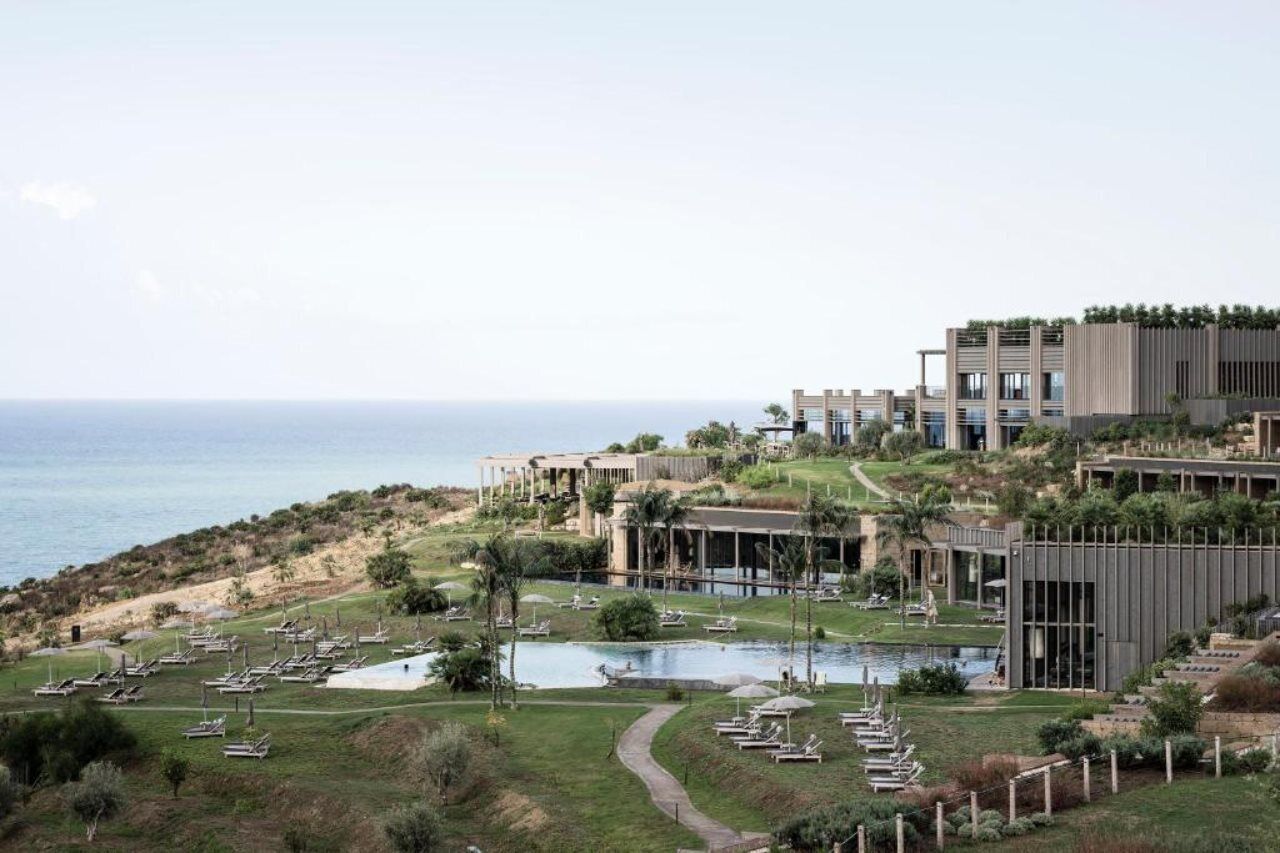 Un resort con varias edificaciones, piscina y vista al mar.