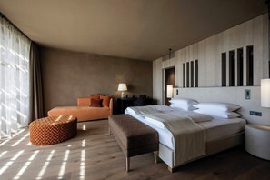 A modern hotel room with a large bed, a sofa, a bench, and a nightstand. - Adler Spa Resort Sicilia (Sicily)