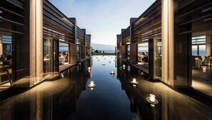 Un pasillo moderno de hotel con suelo reflectante, puertas de vidrio y vista al mar.
