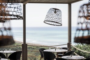 An outdoor dining area with tables and chairs, overlooking a beach and ocean view. - Adler Spa Resort Sicilia (Sicily)