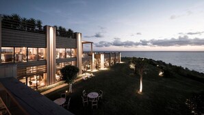 Un bâtiment moderne doté de grandes fenêtres, d’une terrasse et offrant une vue sur la mer.