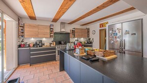 A modern kitchen with wooden beams, a central island, and stainless steel appliances. - Grimaud amazing villa with a swiming pool (GRIMAUD)