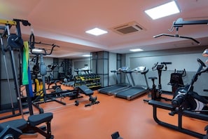 Une salle de sport équipée de divers appareils d’exercice, notamment des tapis de course, des vélos d’appartement et des appareils de musculation.