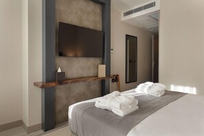 A hotel room with a bed, a mounted TV, a towel rack, and a small table with a tissue box. - Buem Hotel Kosuyolu (Istanbul)