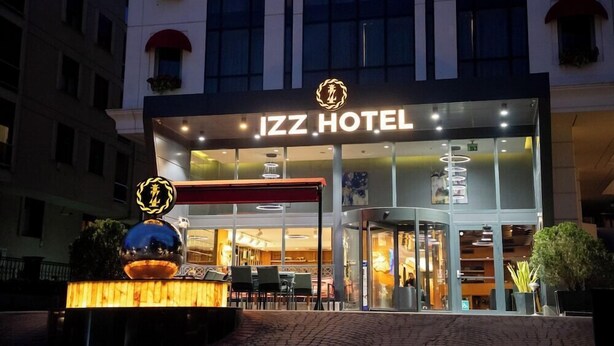 IZZ HOTELs ydre med en moderne facade, store glasvinduer og en markant indgang.