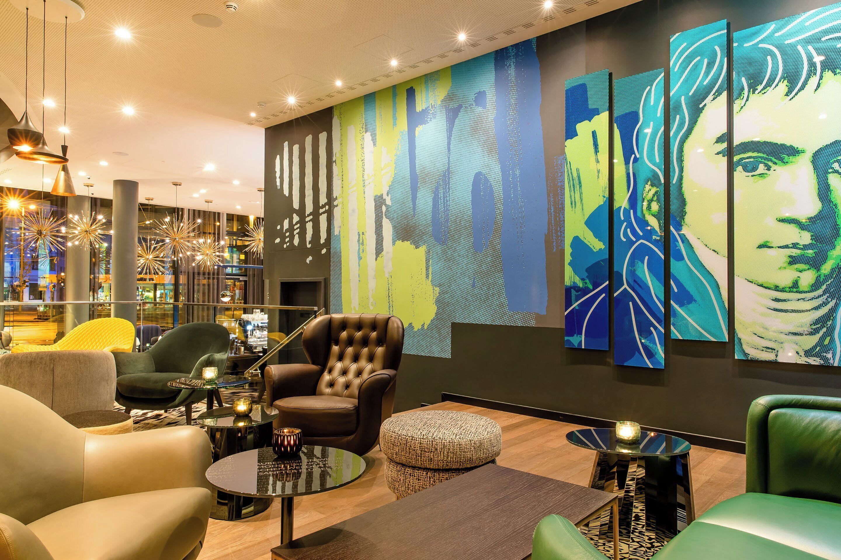 A modern lounge area with leather armchairs, a round coffee table, and a large abstract painting on the wall.