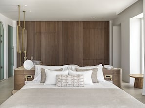 Ein modernes Schlafzimmer mit einem großen Bett, einer Wand aus Holzpaneelen, Nachttischen und einer hängenden Leuchte.