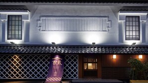 A traditional building with a tiled roof, a wooden gate, and a purple banner with text. - Stay Sakura Tokyo (Tokyo)