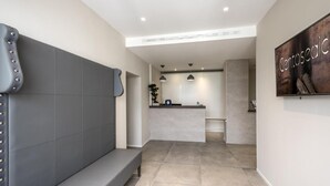 A reception area with a bench, a reception desk, and a wall-mounted sign. - Hotel Centosedici (Terracina)