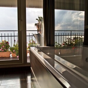 Un balcón con vista al mar, una planta en maceta y una silla de metal.
