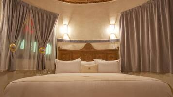 Een hotelkamer met een groot bed, een houten hoofdeinde en een decoratief plafond.