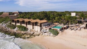 A coastal resort with thatched-roof structures, a swimming pool, and beachside lounge areas. - Our Habitas Tulum (Tulum)