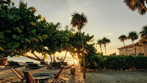 A beach setting with lounge chairs, a hammock, and a stone building in the background. - Our Habitas Tulum (Tulum)