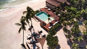 An aerial view of a beachside resort with a swimming pool, lounge chairs, and palm trees. - Our Habitas Tulum (Tulum)