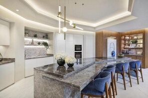 Uma cozinha moderna com uma ilha central, banquetas e eletrodomésticos embutidos.