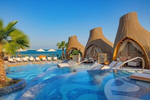A pool with lounge chairs and a building with unique architecture. - Waldorf Astoria Lusail Doha (Lusail)