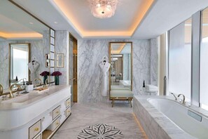 A luxurious bathroom with marble walls, a large bathtub, and a vanity with gold fixtures. - Waldorf Astoria Lusail Doha (Lusail)