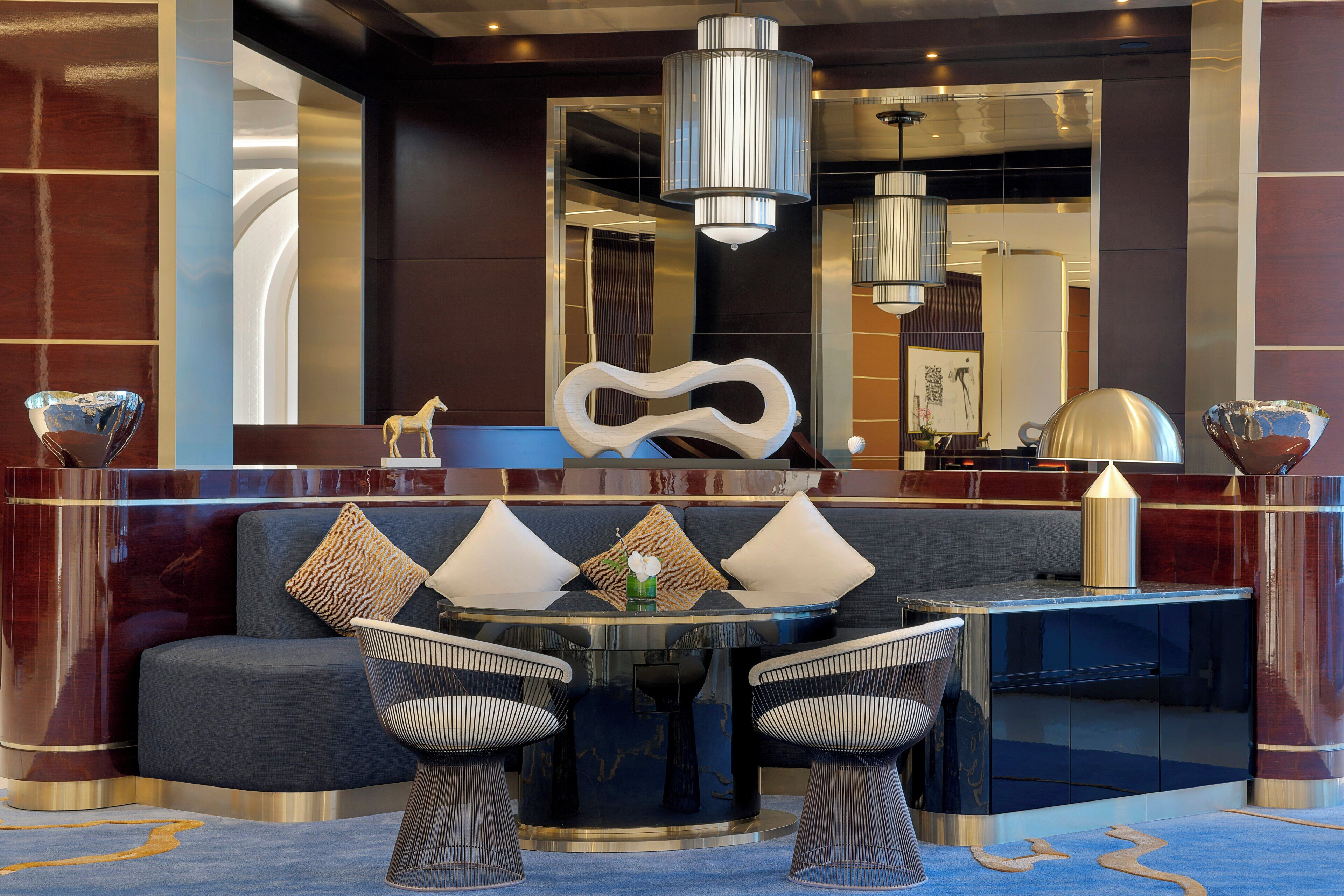 A modern lobby with a round table, two chairs, a sofa, and a decorative wall piece.