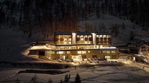 Um hotel de vários andares com um letreiro chamativo 'Grand Hotel Cervino' em uma área montanhosa coberta de neve.