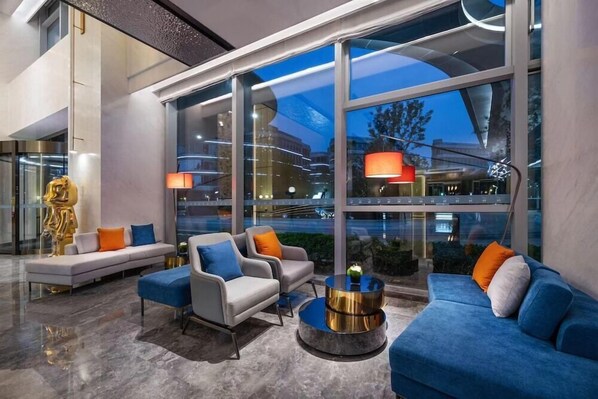A modern lobby with a sofa, armchairs, and a coffee table. Large windows offer views of the cityscape. - Novotel Shanghai Caohejing (Shanghai)