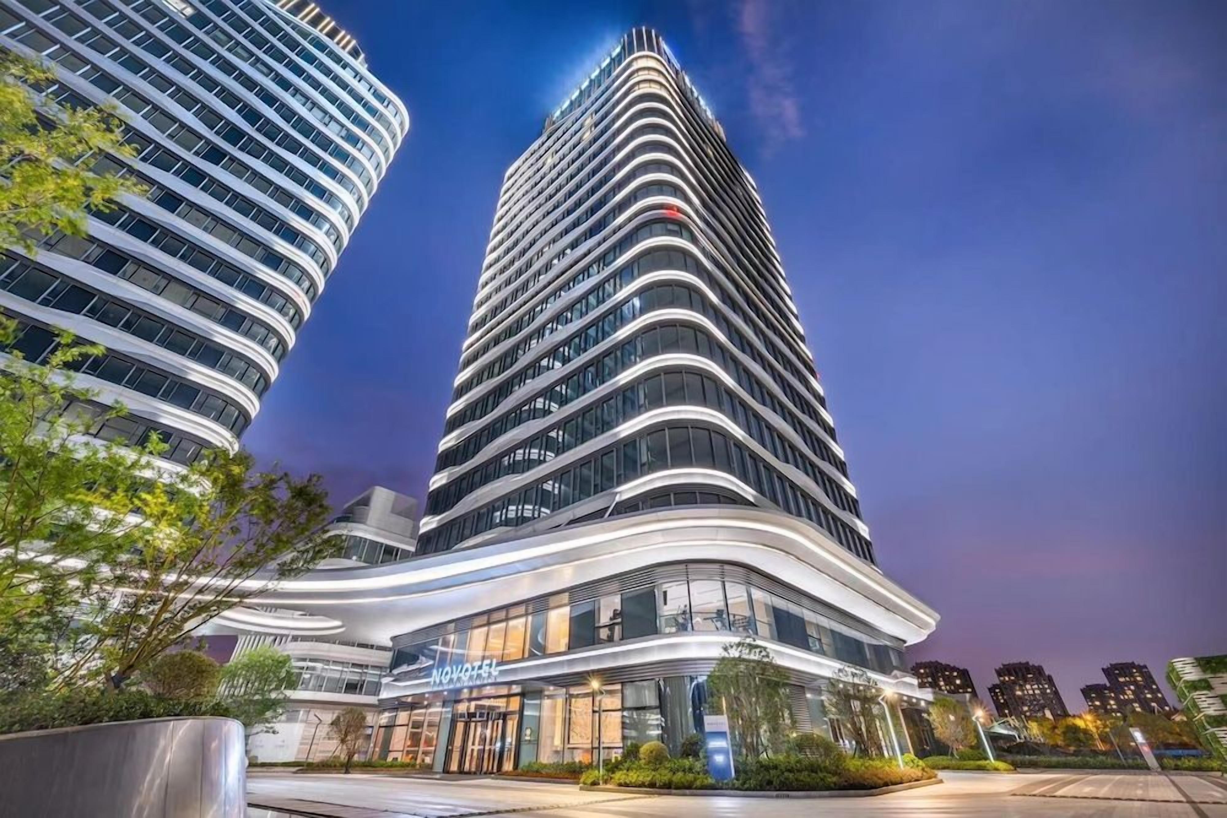Un hôtel moderne à la façade incurvée, doté de plusieurs étages et d’une entrée imposante avec une enseigne.