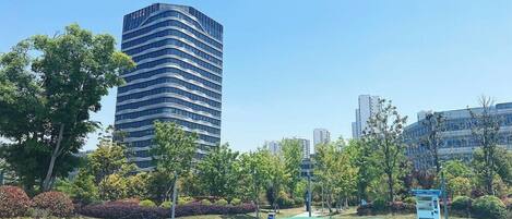 A modern building with a curved facade, surrounded by lush greenery and a clear blue sky.