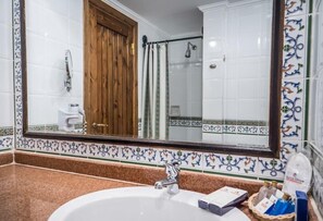 Ein Badezimmer mit einem weißen Waschbecken, einem großen Spiegel und einer Duschkabine.