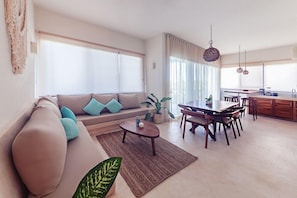 A modern living room with a sofa, coffee table, and dining area.