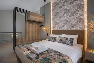 Un dormitorio moderno con una cama grande, cabecera de madera, pared con diseño y un balcón con barandilla.