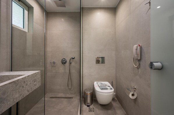 Une salle de bain moderne avec une douche à parois de verre, des toilettes et un lavabo en marbre.