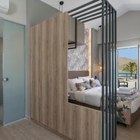 Un dormitorio moderno con un armario de madera, una cama con ropa de cama estampada y vistas al exterior.