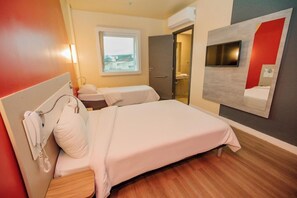 A hotel room with a bed, bedside table, and a TV mounted on the wall. - Ibis Budget Capao Bonito (Capao Bonito)