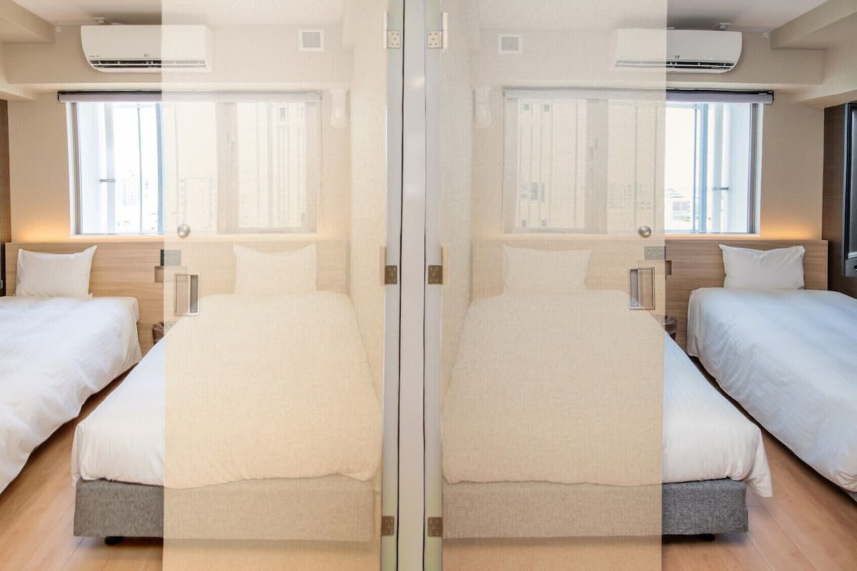 A mirrored room with two beds, a window, and an air conditioning unit.