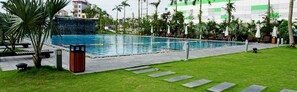 A swimming pool with a waterfall feature, surrounded by a well-maintained lawn and palm trees. - Central Hotel Thanh Hoa (Thanh Hoa)
