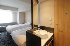 A hotel room with two beds, a large mirror, a round sink, and a wooden door. - JR Inn Sapporo N2 (Sapporo)