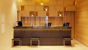 A modern reception desk with a marble top, wooden shelving above, and a security camera above. - JR Inn Sapporo N2 (Sapporo)